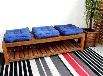 Wooden bench with blue cushions on a striped rug